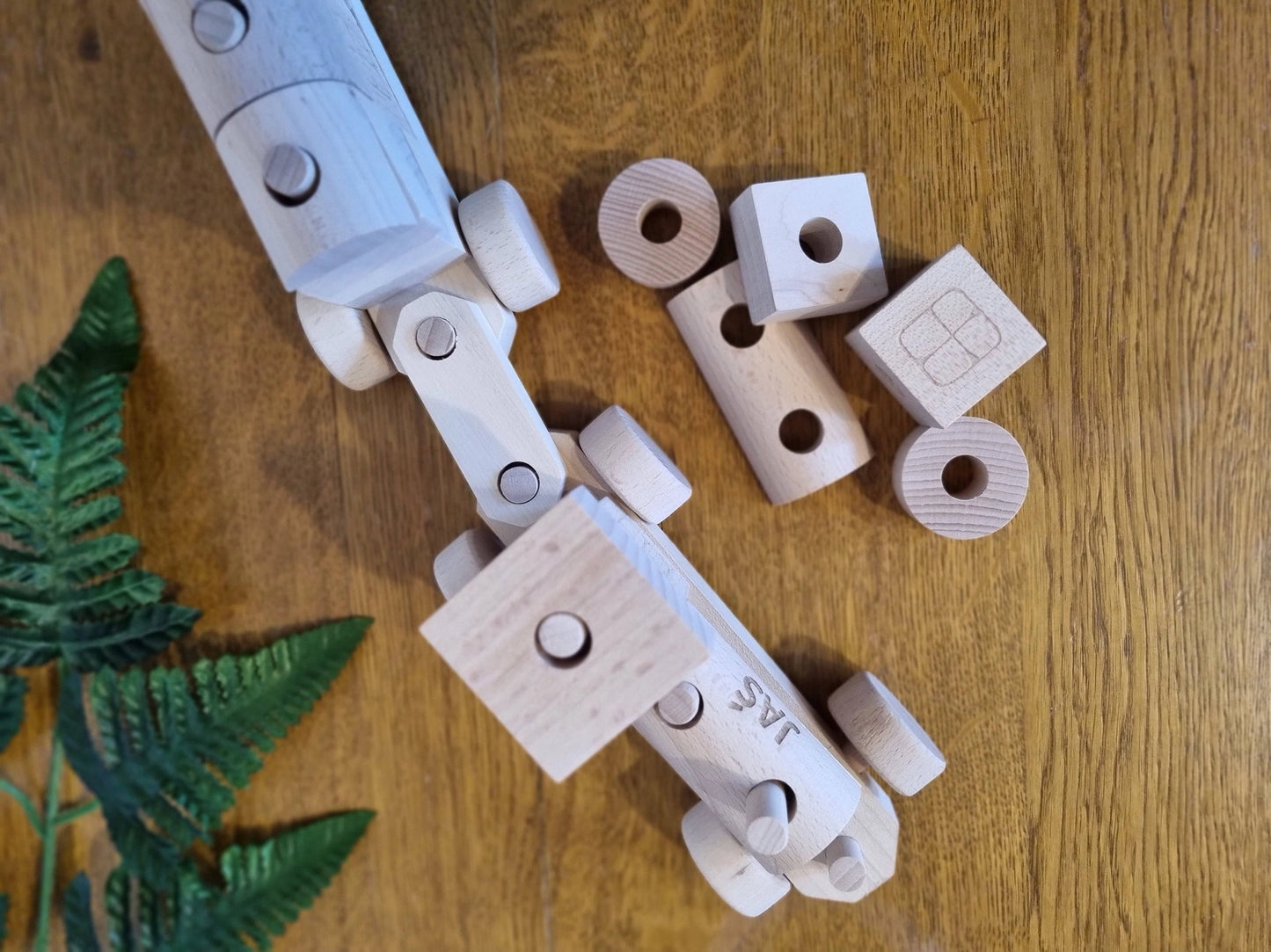 Wooden Toy Train with Stacking Blocks on a wooden floor next to plant leaves