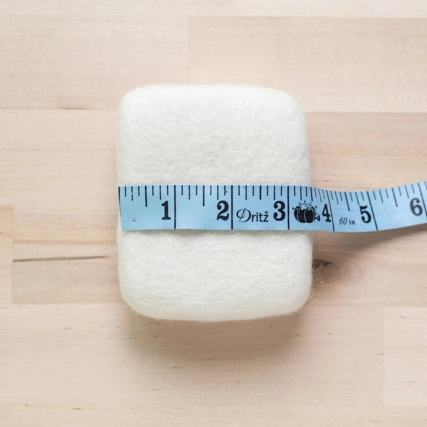 Small Wool Needle Felting Mat with a blue measuring tape on a wooden surface
