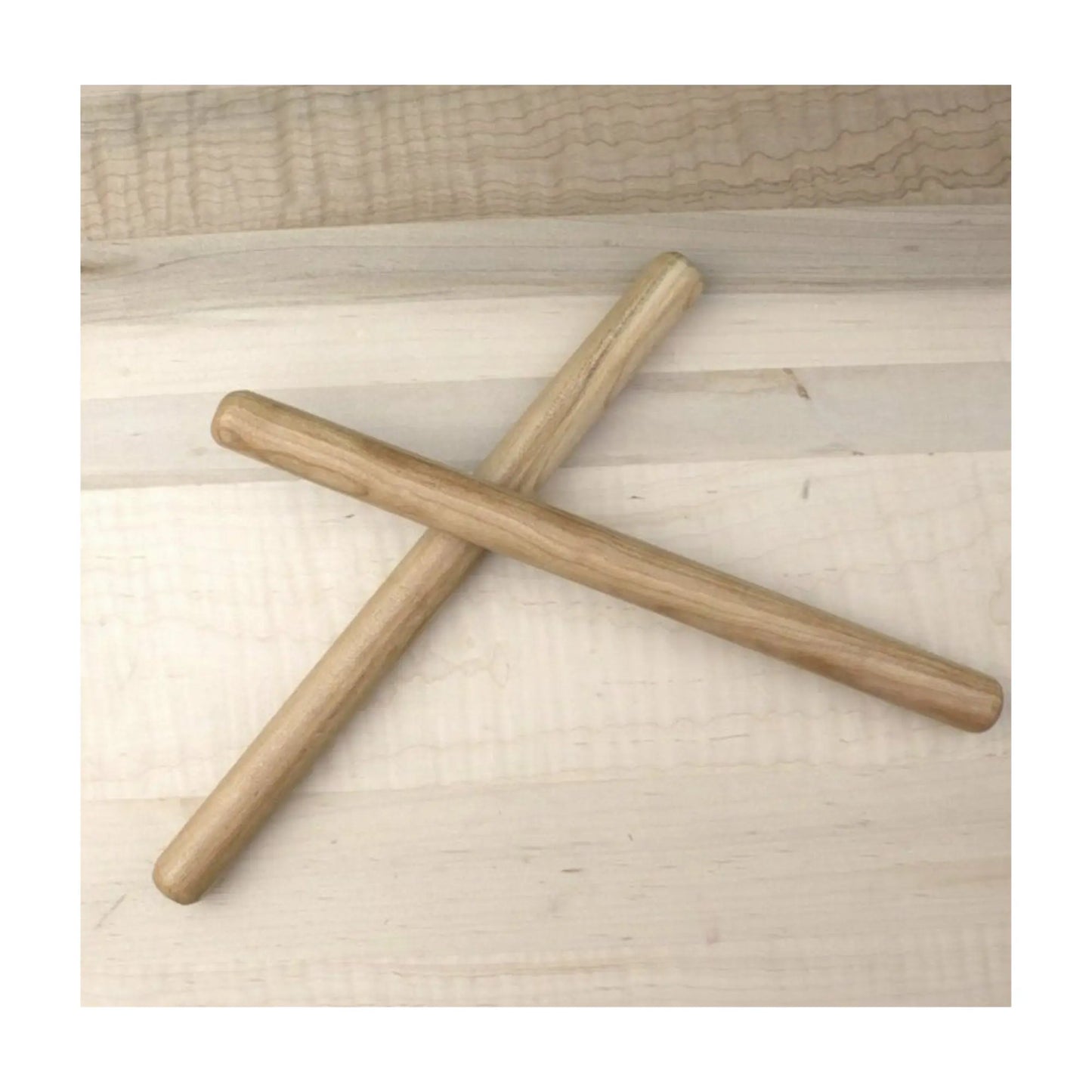 Two Wooden Rhythm sticks made from cherrywood hardwood criss crossed on a tabletop