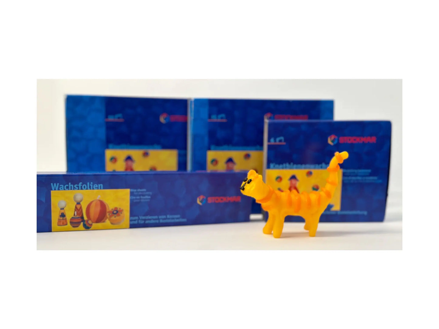 Stockmar boxes showing the different sizes with an orange and yellow modeling beeswax cat