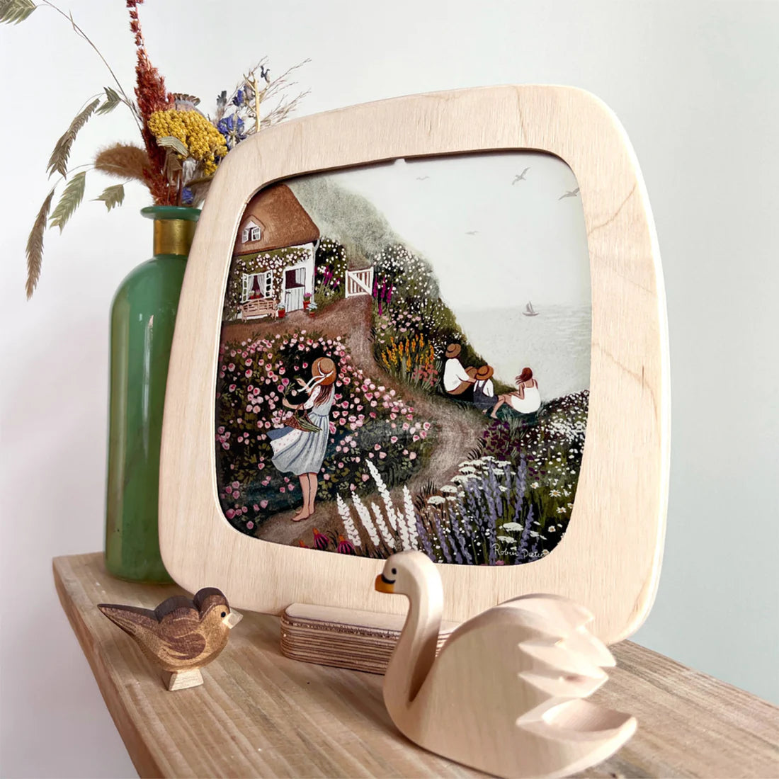 Wooden Toverlux frame in a base stand with a scene of a garden and house