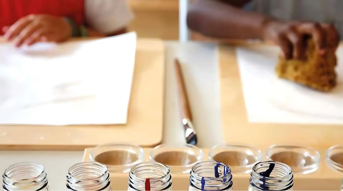 Table with children's hands with watercolor paper on a wooden paint board