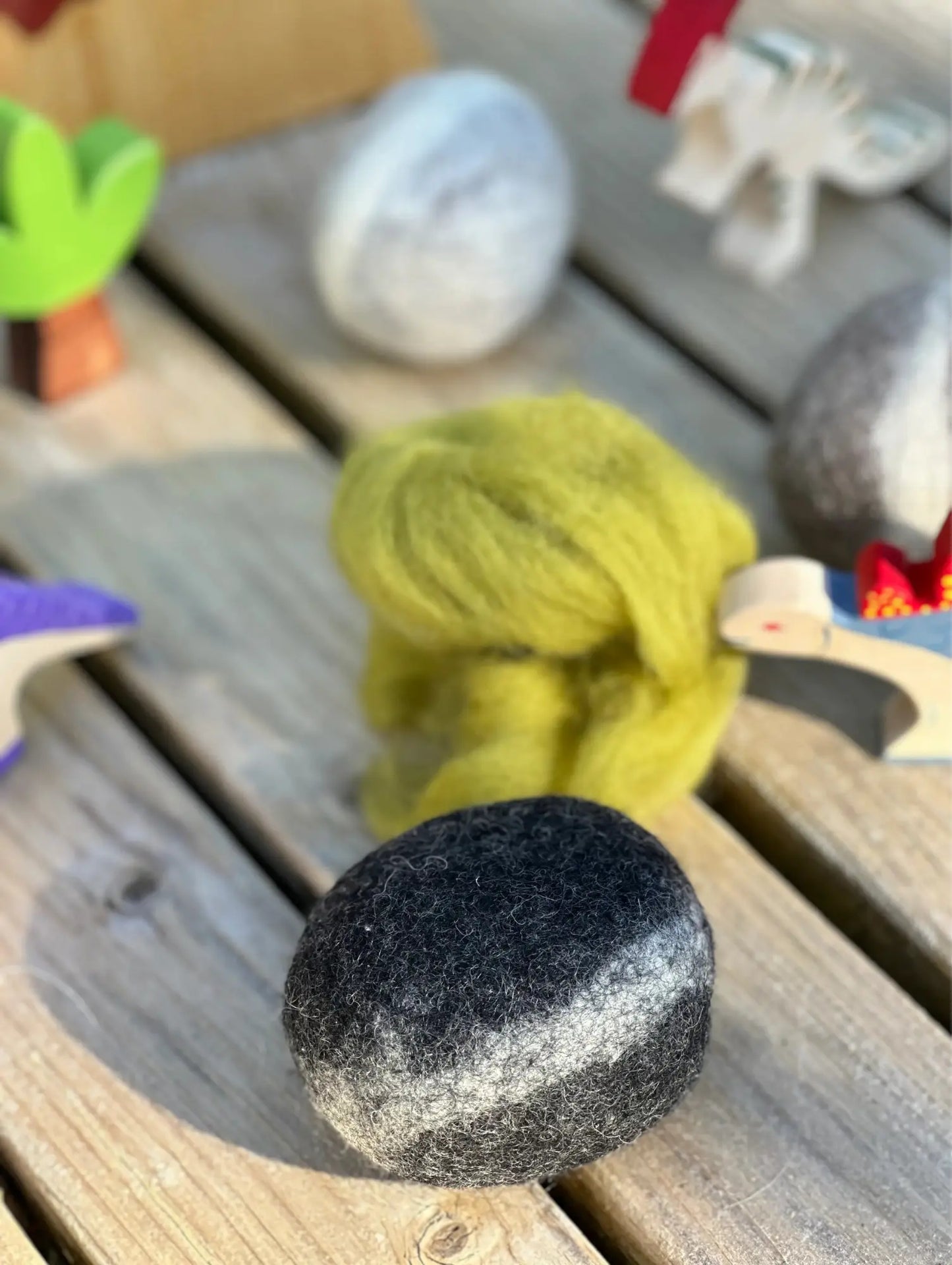 Black stone and green yarn on a wooden surface with blurred background