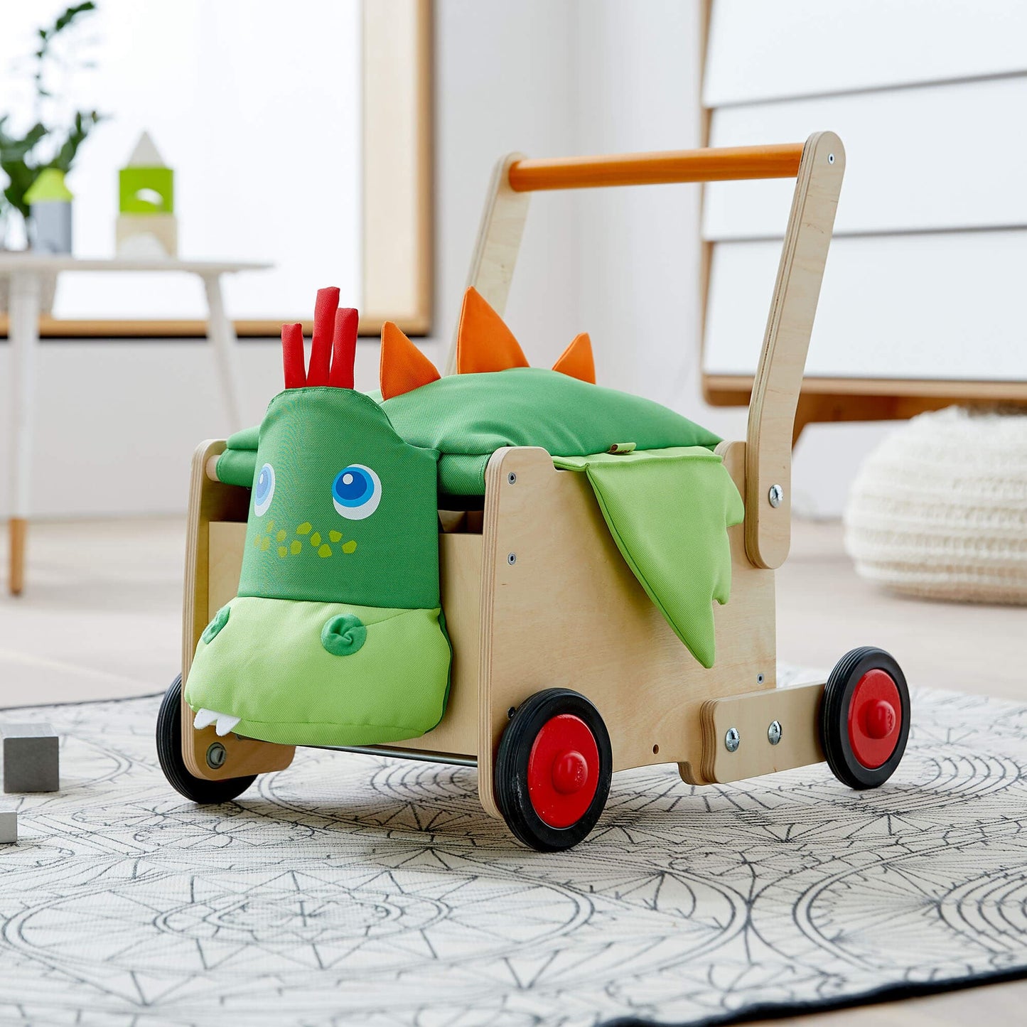 Children's toy dinosaur cart with green dinosaur design on a light wooden floor.