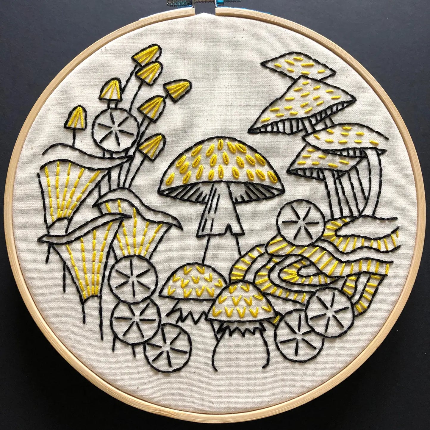 Overview of a finished mushroom embroidery kit on black background