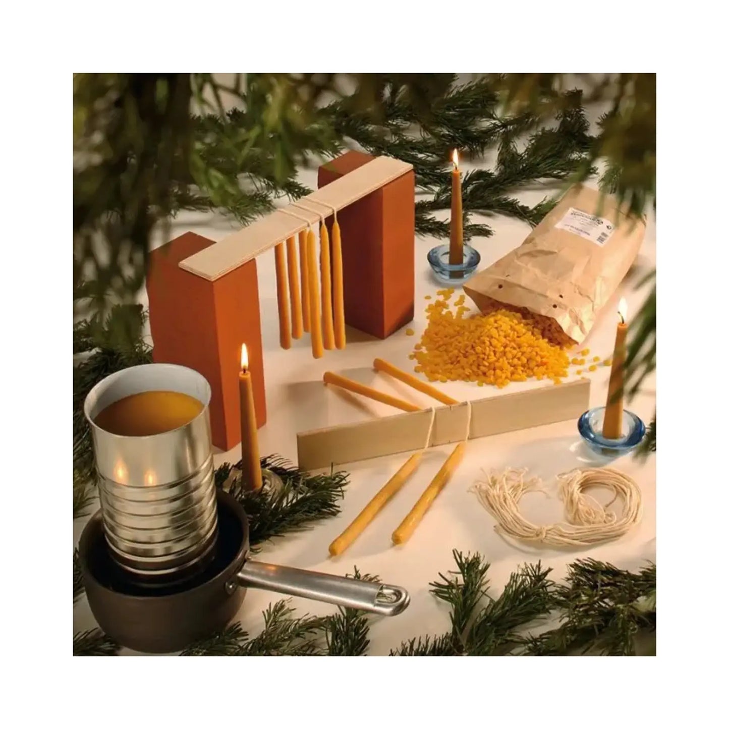 Candle-making materials and tools on a table with a Christmas tree in the background