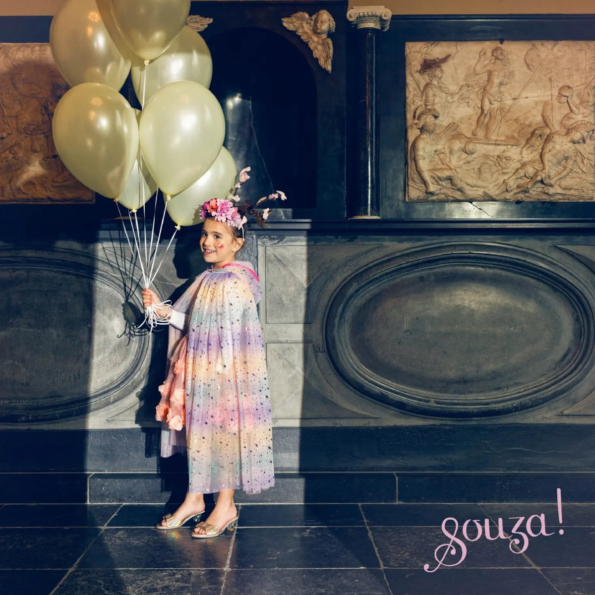 Child wearing rainbow dress-up cape for storytelling and imaginative play