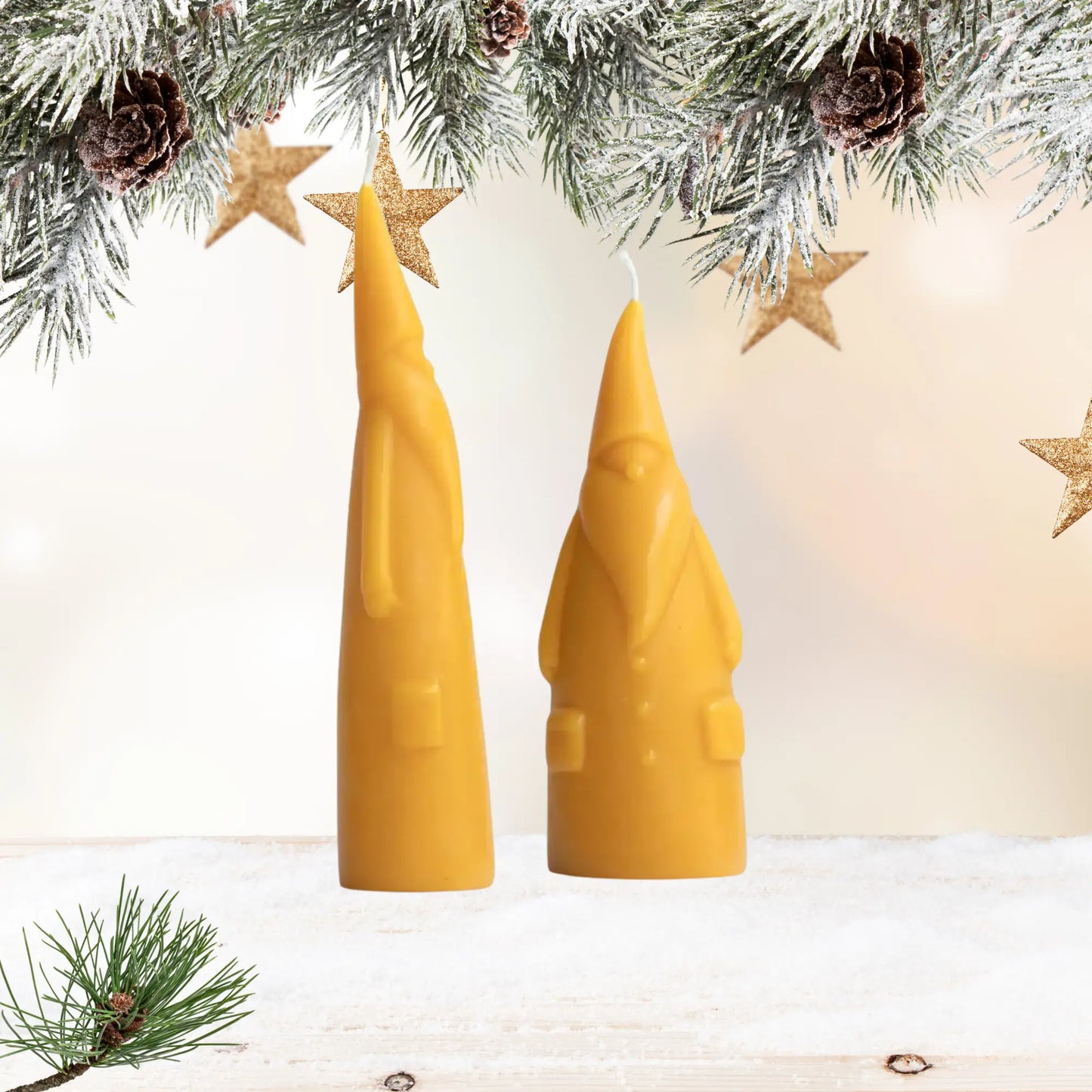 Two beeswax santa candle under a Christmas garland with decorations.