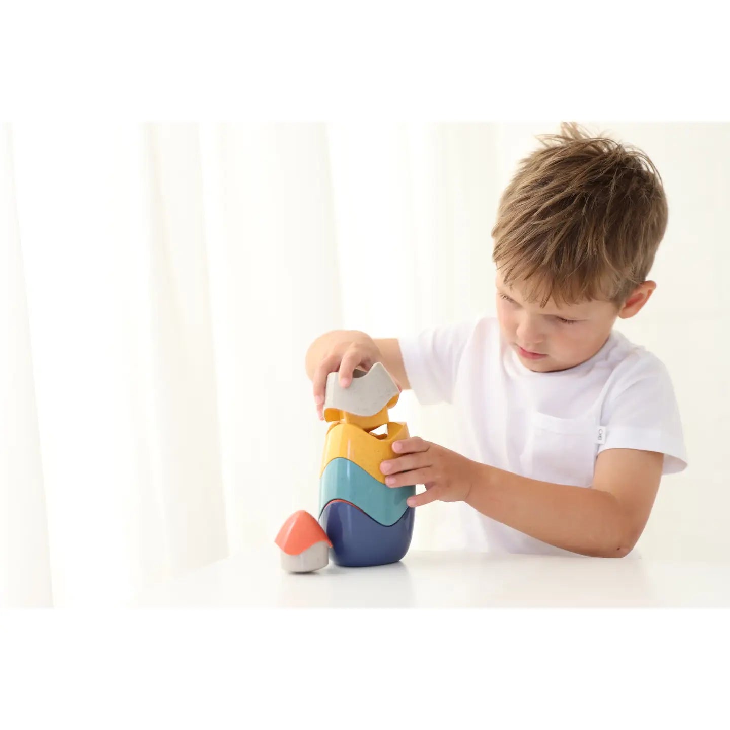 Child playing with a colorful nesting toy on a white background