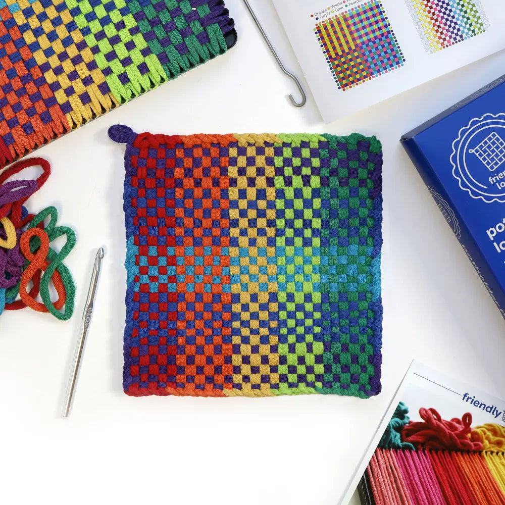 Colorful woven fabric with crochet tools and pattern books on a white surface