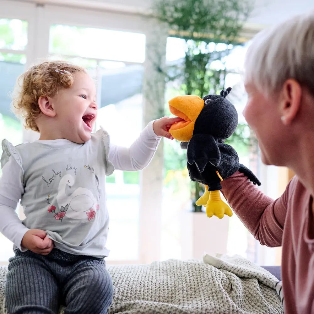 Child feeding Theo the Raven glove puppet