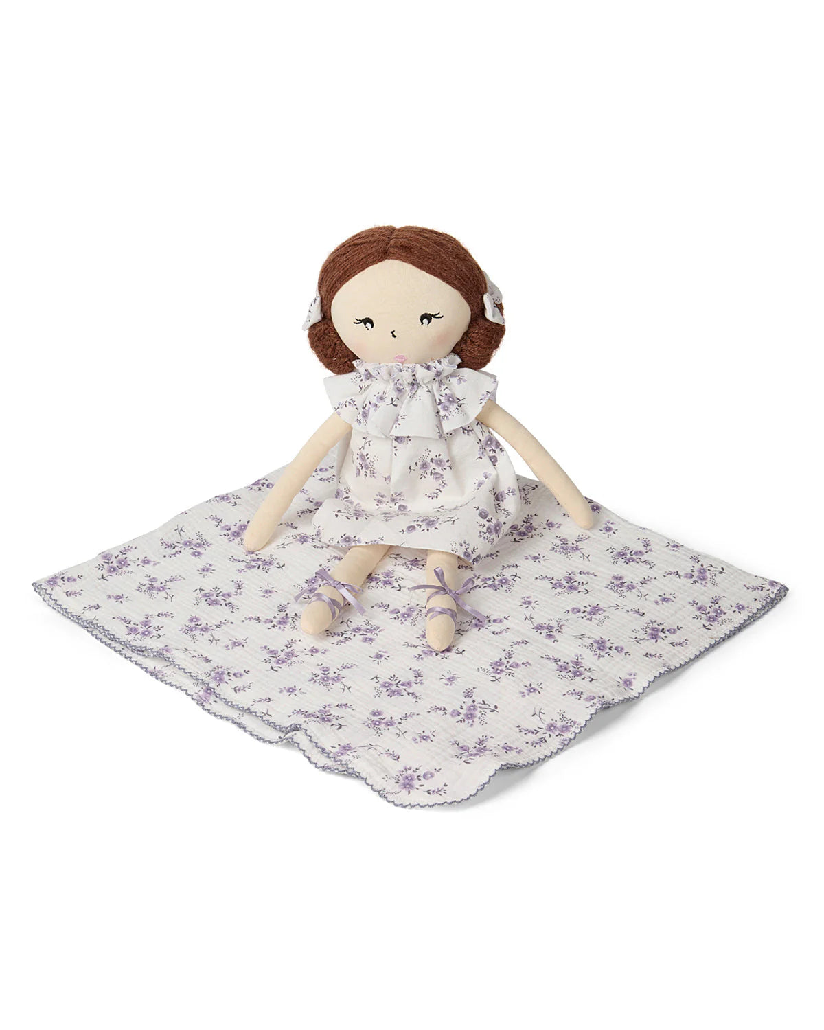 Doll with a floral dress on a matching blanket against a white background