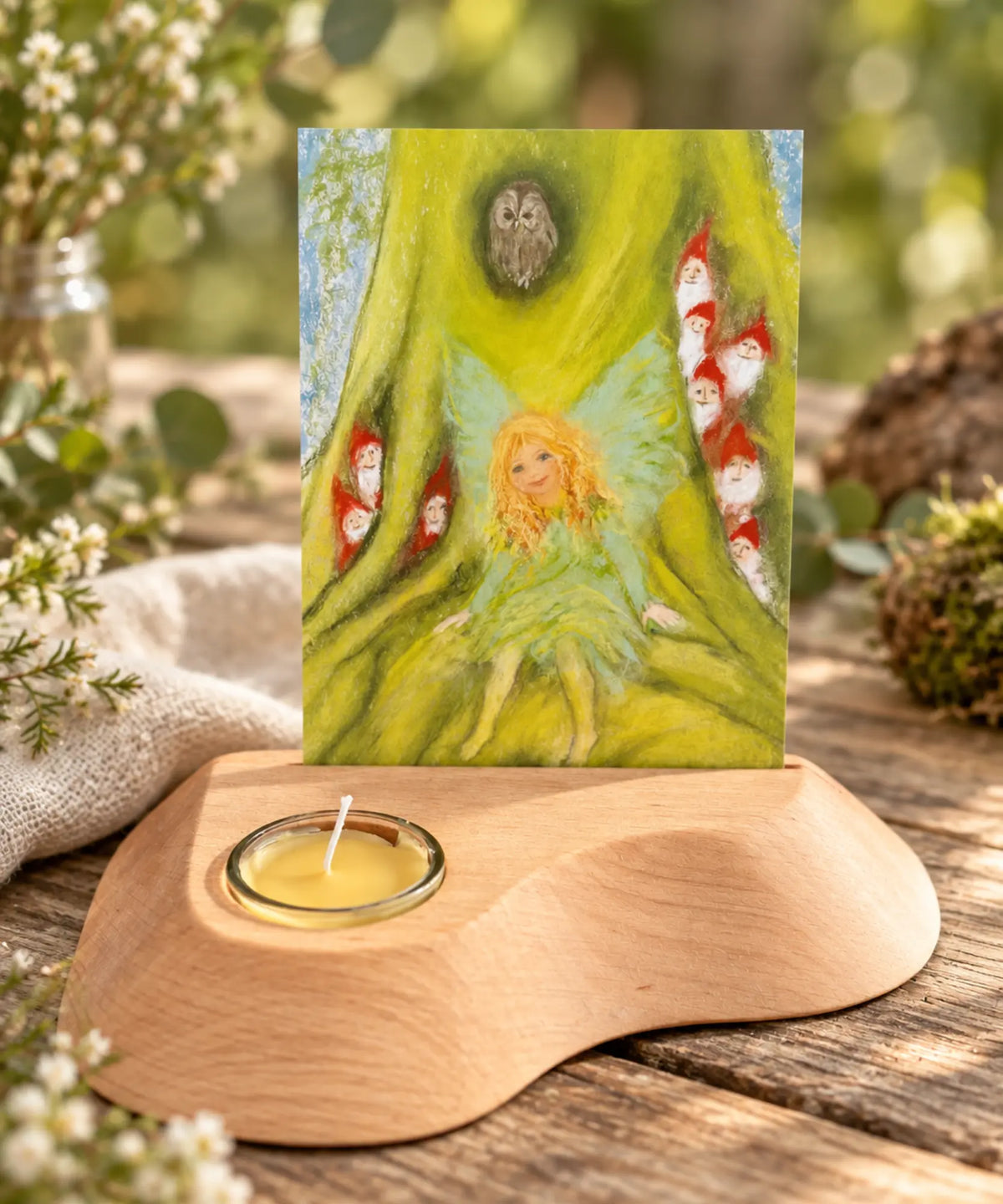 Marjan van Zeyl Tree Fairy and Gnomes postcard displayed in a wooden candle holder with flowers and greenery on a Waldorf-inspired nature table.