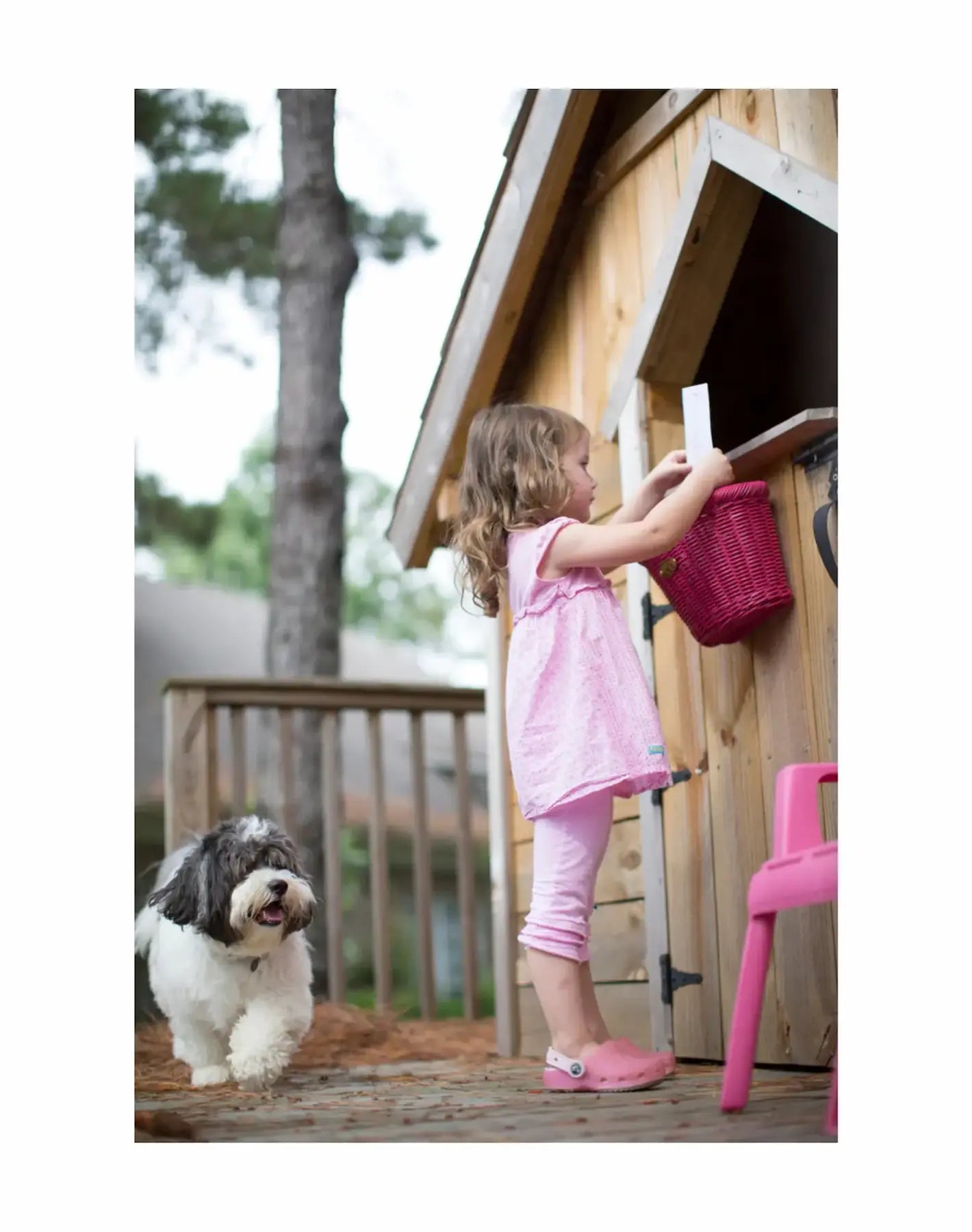 Child playing with a dog near a wooden playhouse