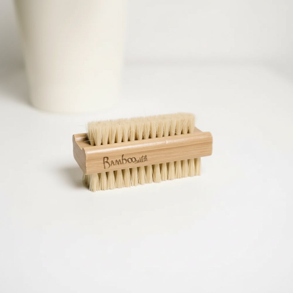 Bamboo and sisal nail brush on a white surface with a white cup in the background