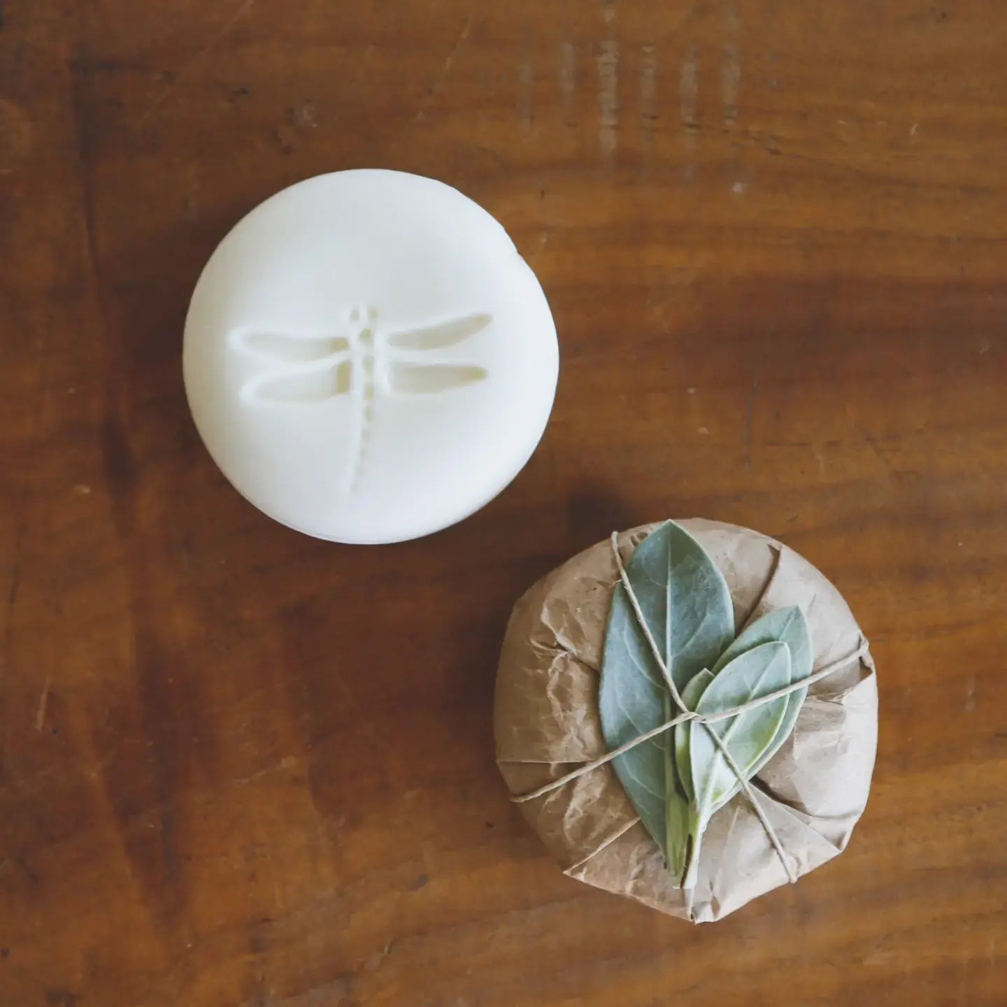 White round olive oil soap with dragonfly design on a wooden surface