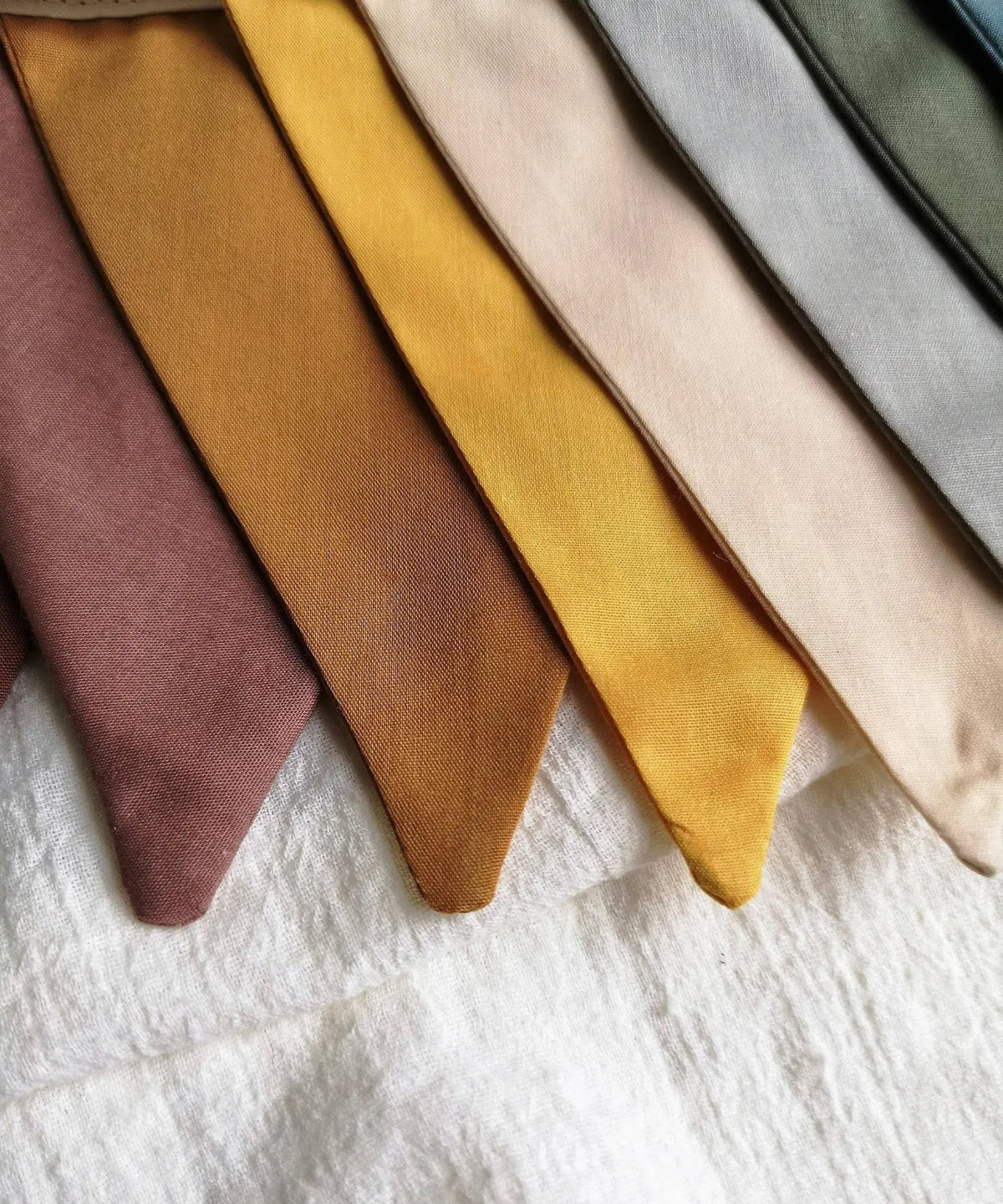 Close-up of the linen pennant garland showing muted pink, ochre, mustard, beige, gray, olive and blue flags.