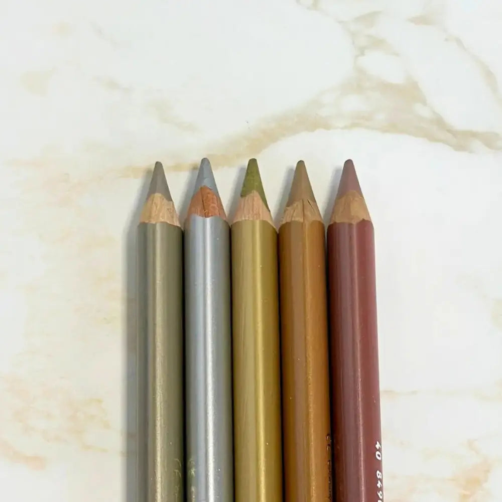 Five metallic colored pencils on a marble background