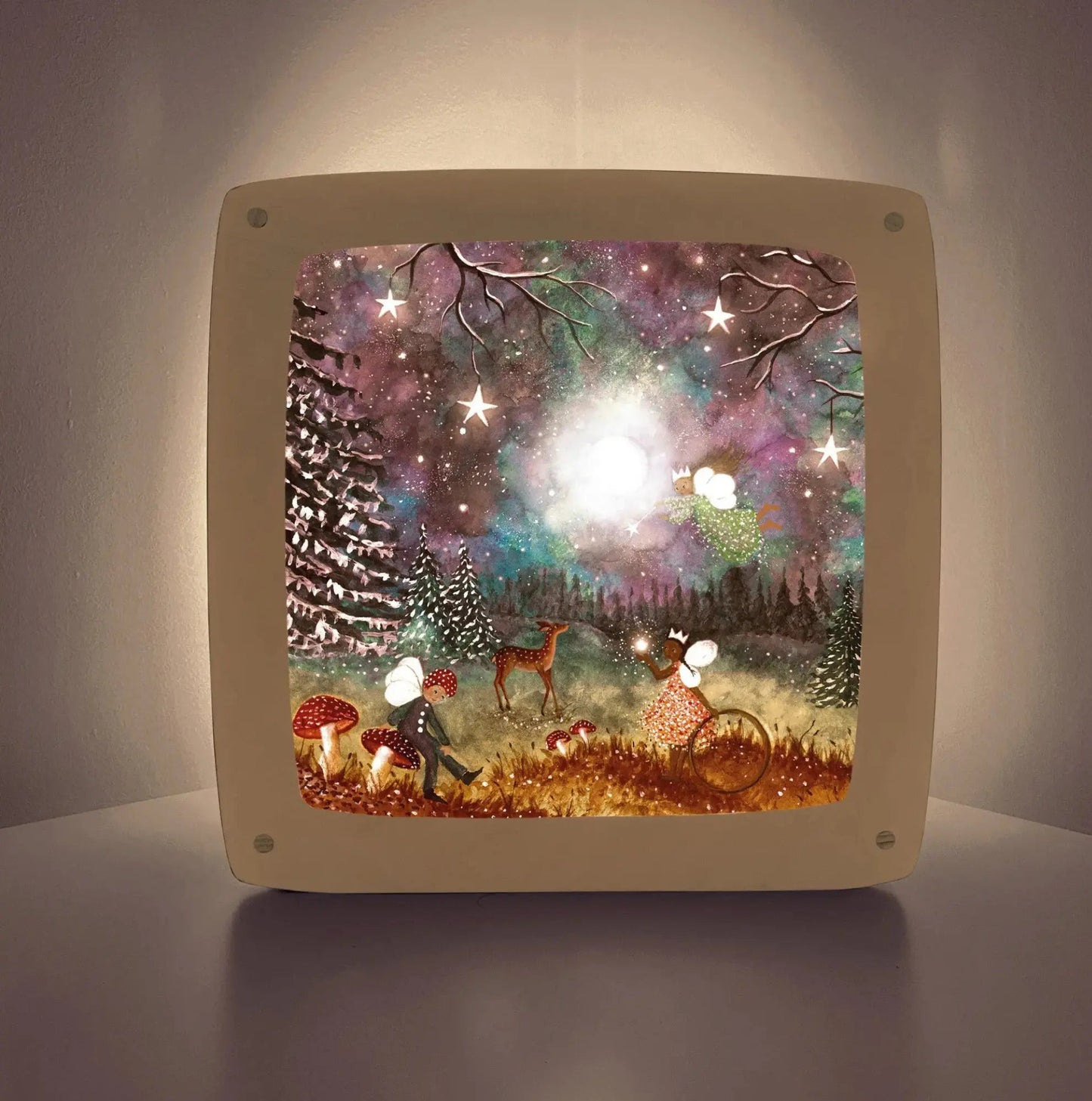 Decorative Toverlux lamp glowing with a fairy tale design featuring trees, stars, and a deer.