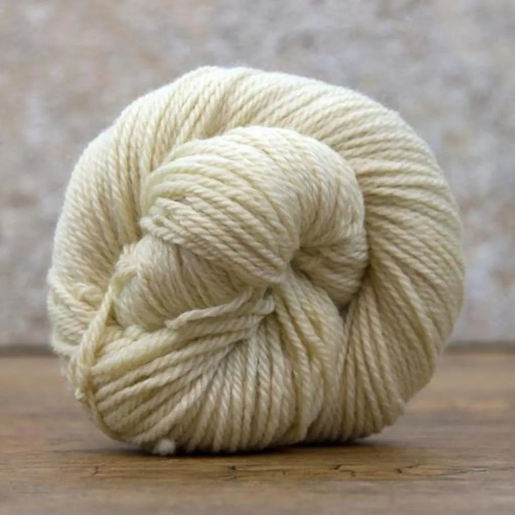 Undyed Bluefaced Leicester wool yarn on a rustic wooden surface