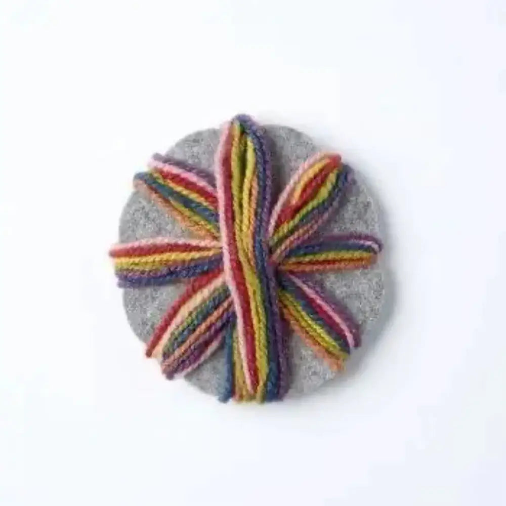 Round gray stone with a colorful yarn twist on a white background