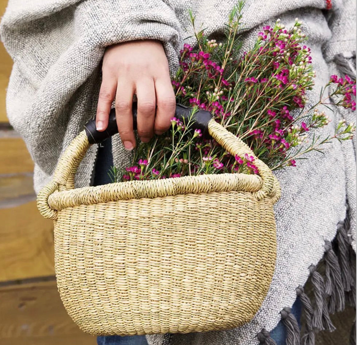 Child's hand holding a Baby Bolga Gathering Basket with Purple Flowers on green stems