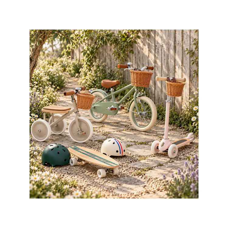 Banwood tricycle, bike, scooter, skateboard, and helmets in a garden setting