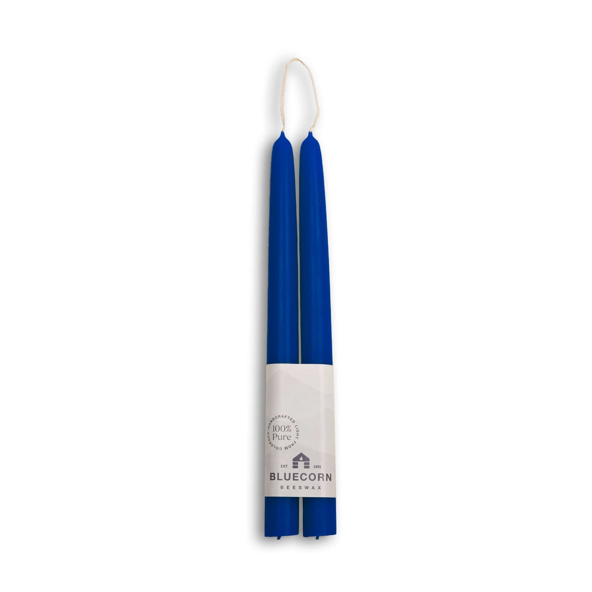 Two blue candles with a white label on a white background
