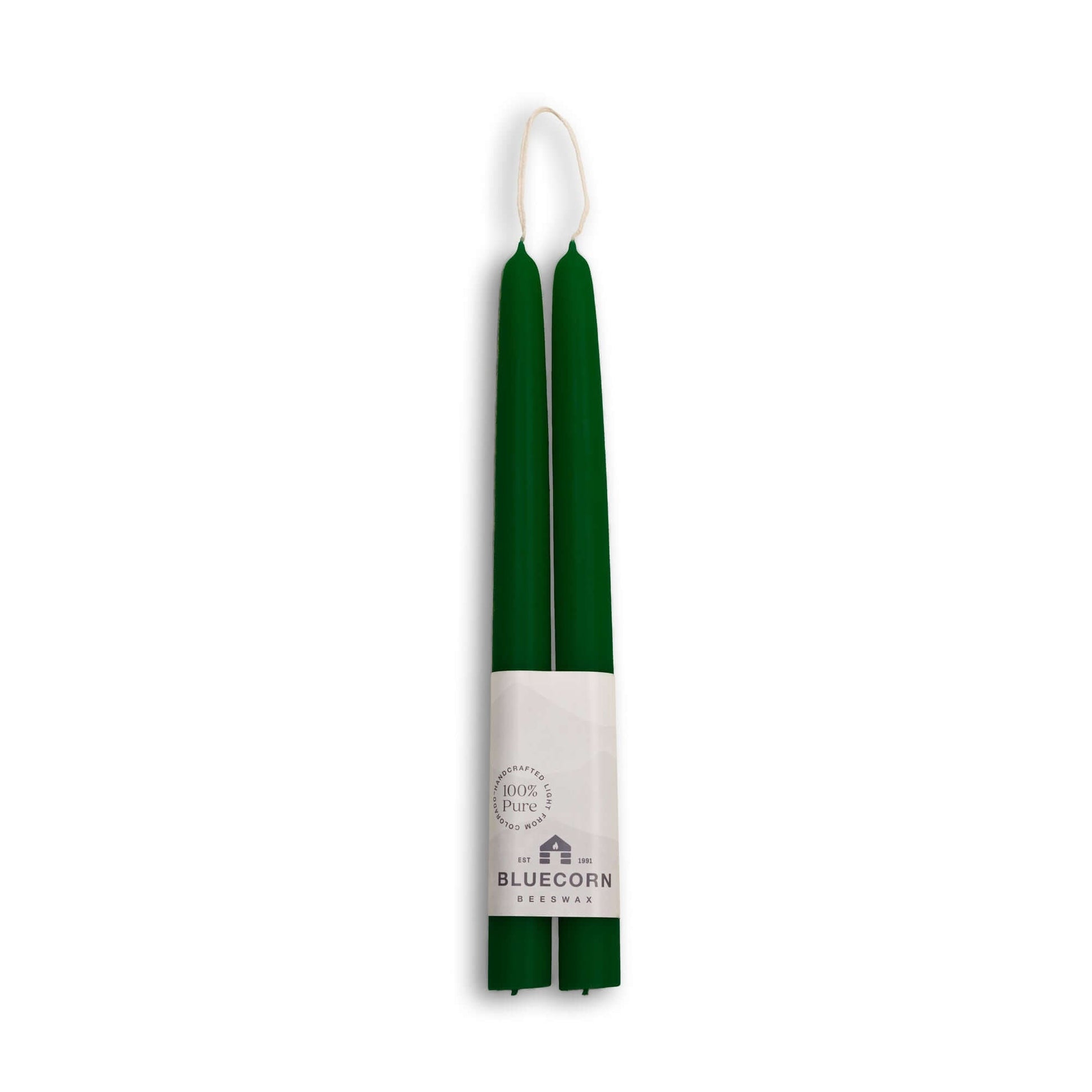 Two green candles in a white holder with Bluecorn Harvest branding on a white background
