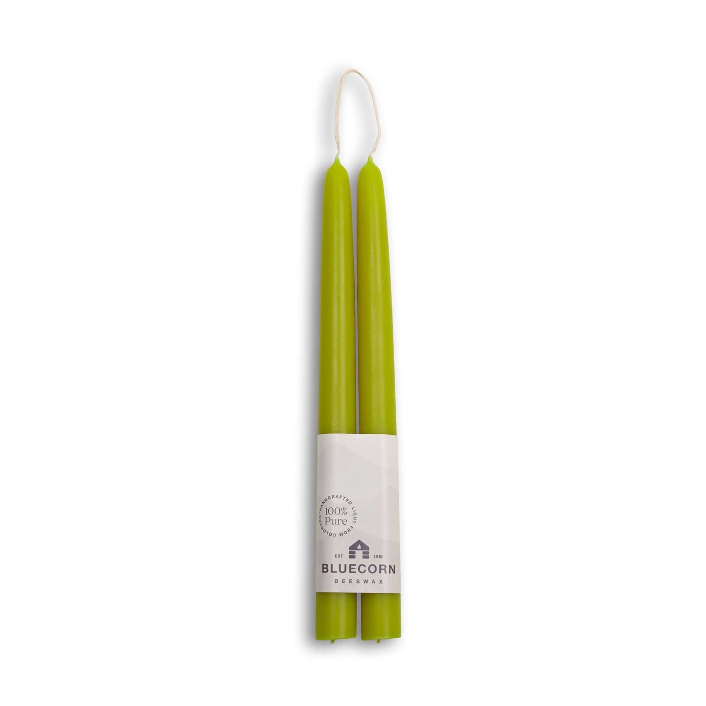 Two green candles in a white holder with Bluecorn Harvest branding on a white background