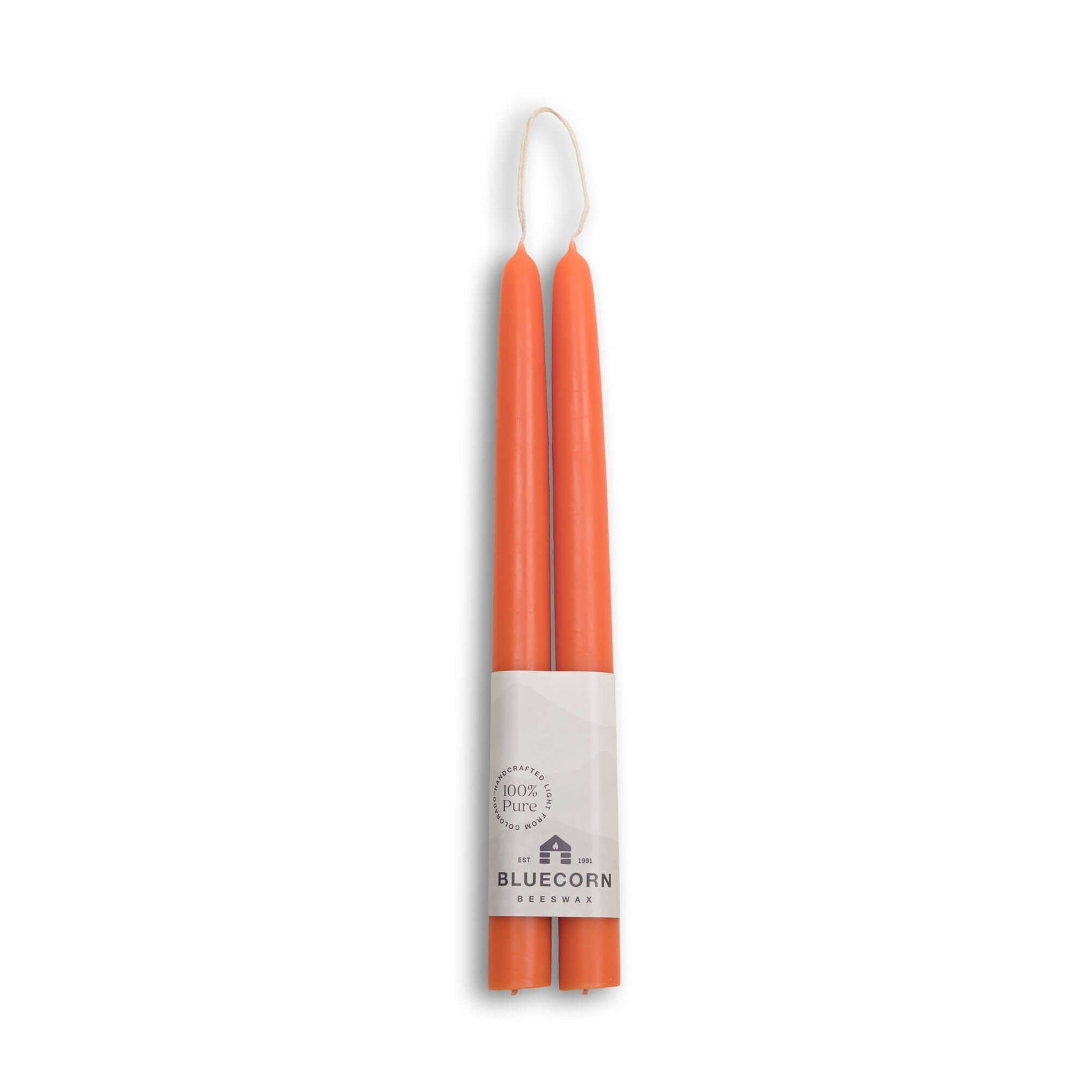 Two orange candles in a cardboard holder with 'Bluecorn' branding on a white background