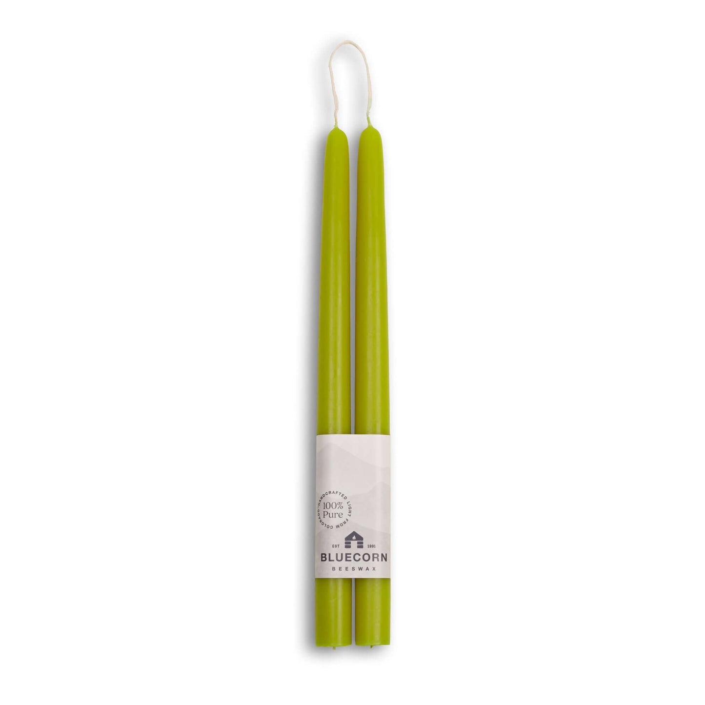 Two green candles in packaging with a brand label on a white background
