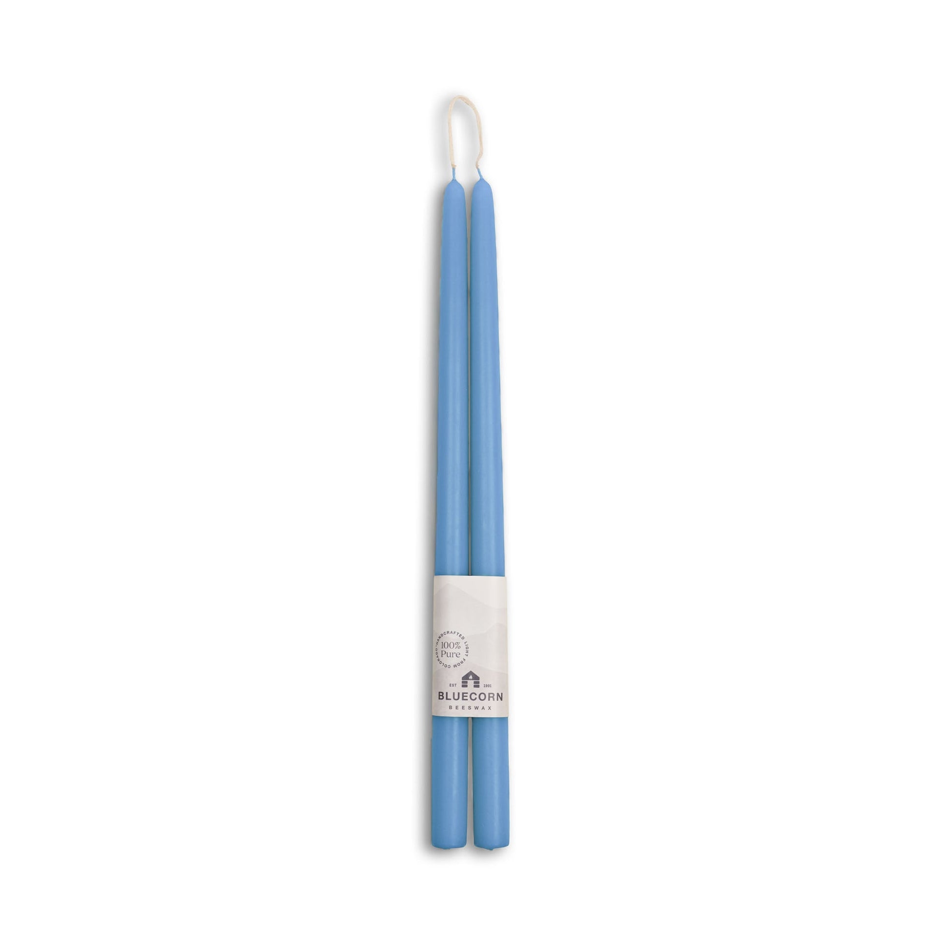 Two blue candles with a white label on a white background