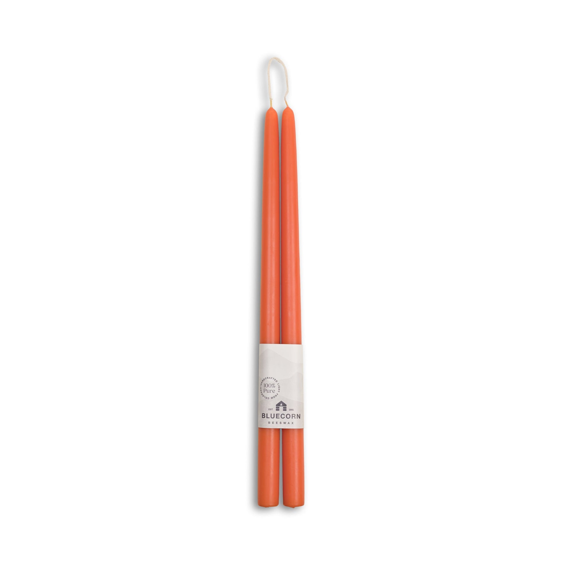 Pair of orange candles with a white label on a white background