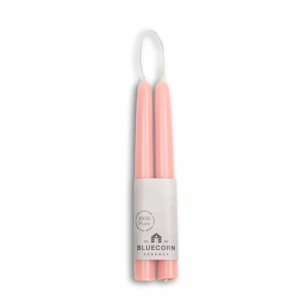 Two pink candles in a white holder with 'Bluecorn' branding on a white background