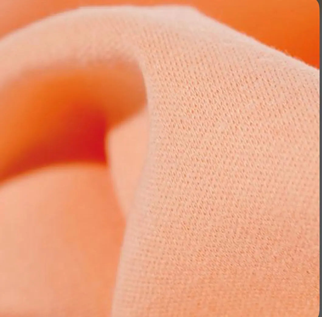 Close-up of textured apricot organic cotton tricot dollmaking fabric