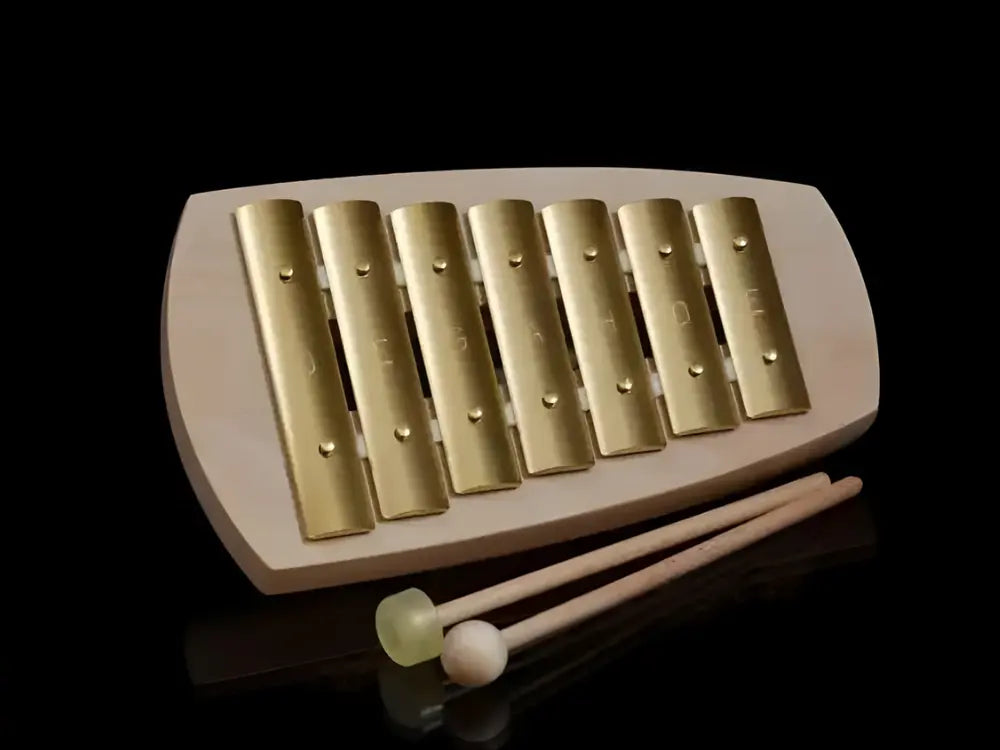 Wooden xylophone with gold keys and two mallets on a black background