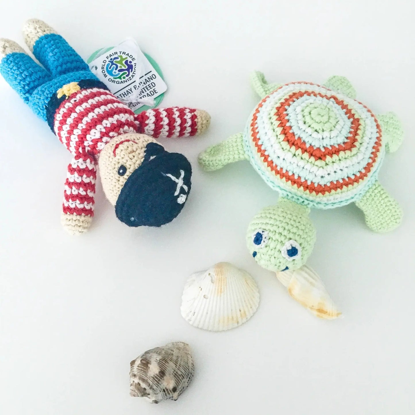 Top down view of knitted sea turtle rattle next to another handmade doll toy