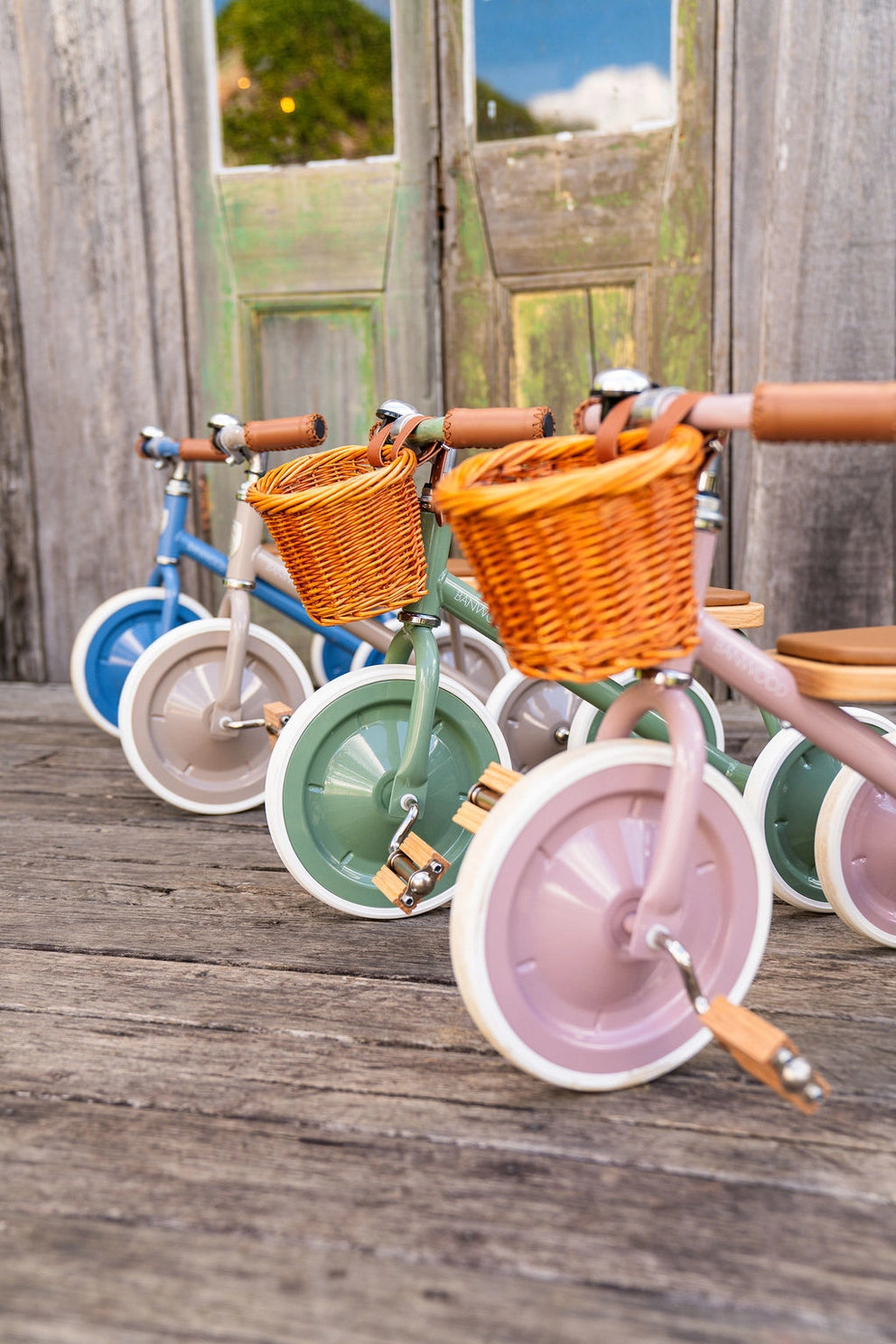 Colorful children's bikes with baskets on a wooden deck