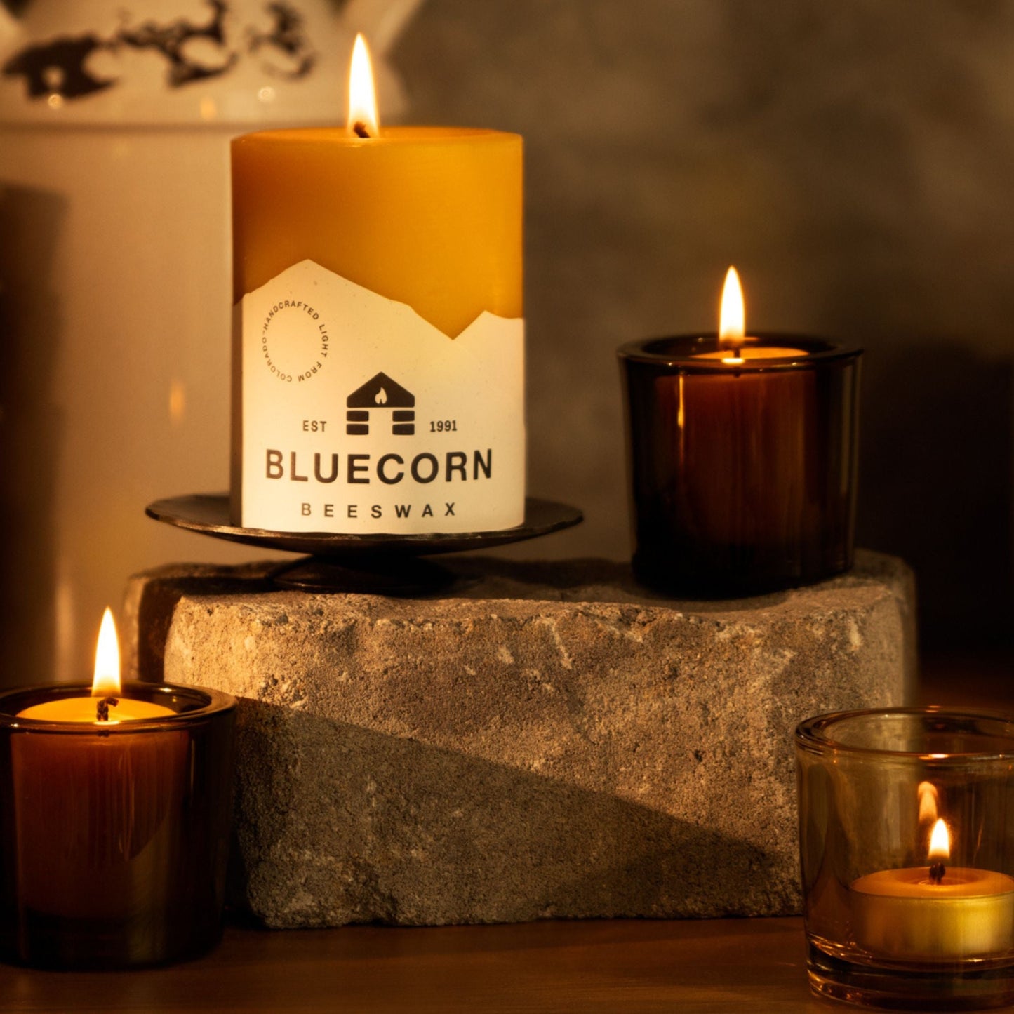 Bluecorn Beeswax candle on a stone block with other candles in the background