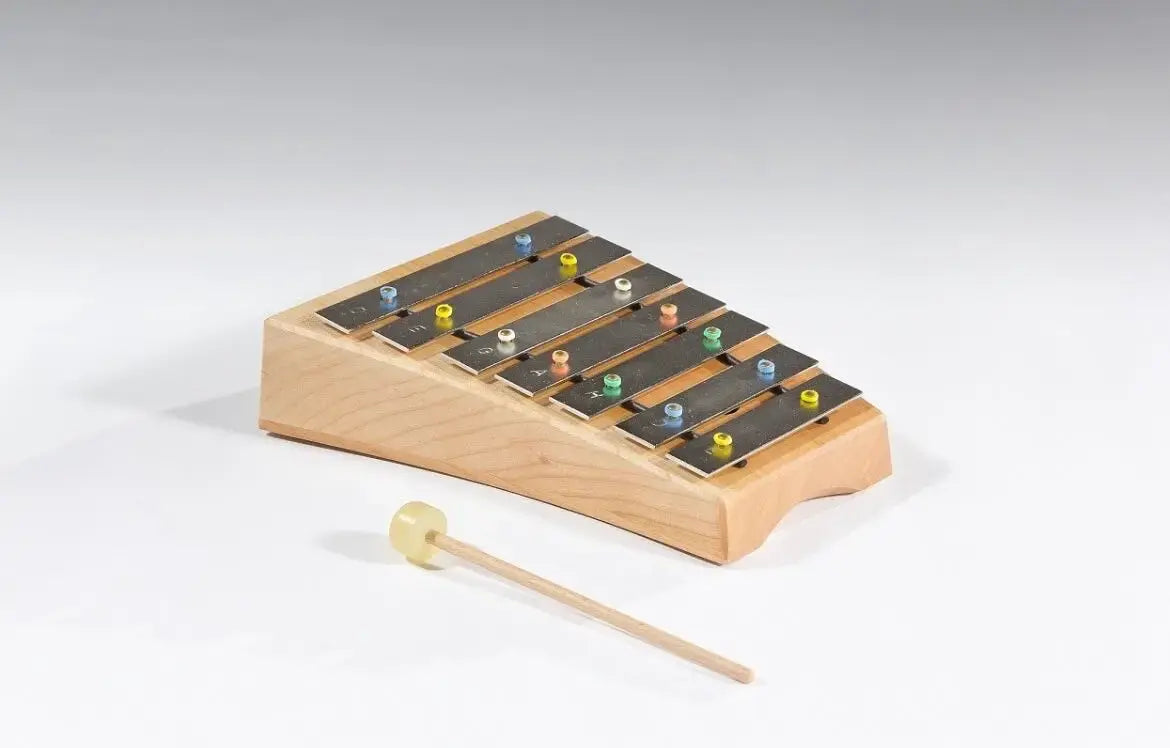 Wooden xylophone with metal bars and a wooden mallet on a white background