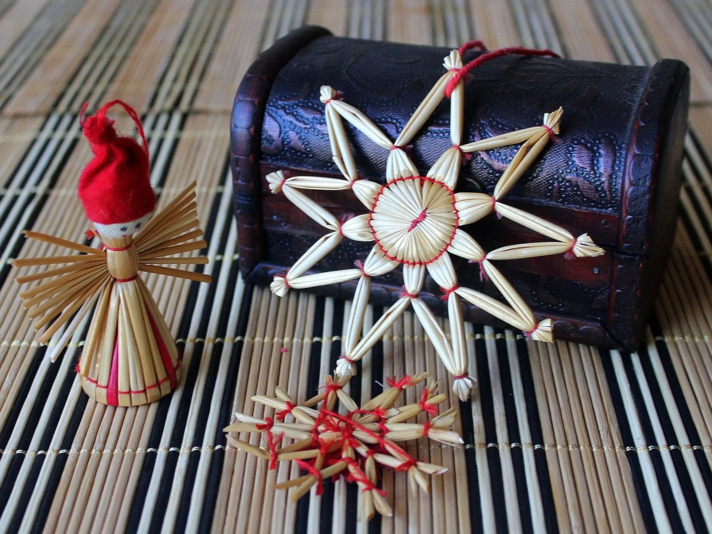 Decorative straw star ornaments with a small figurine on a striped mat