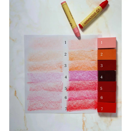 Color swatches of doll making crayons on a marble surface