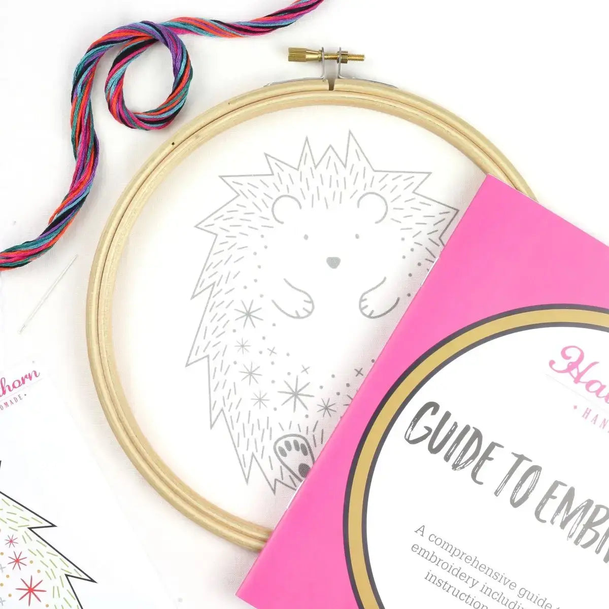 Embroidery hoop with hedgehog design and pink guide on a white background