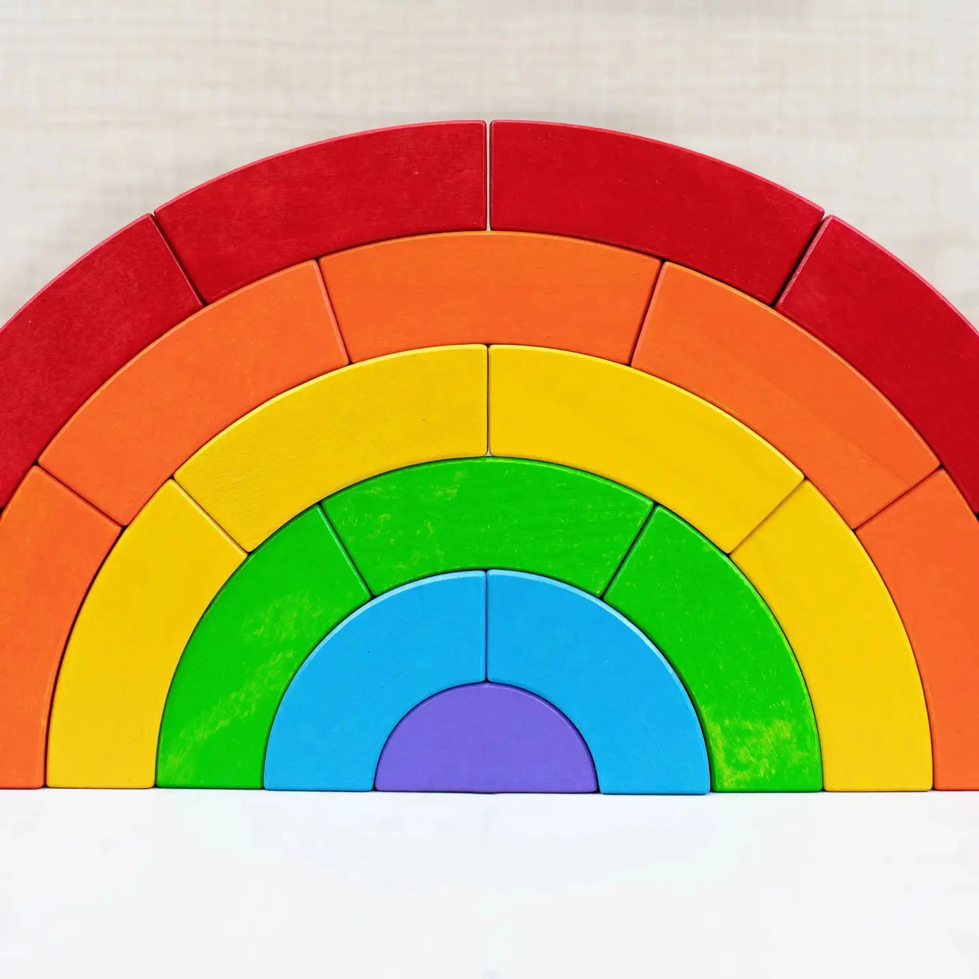 Colorful rainbow blocks in an arch made of wooden blocks on a white background