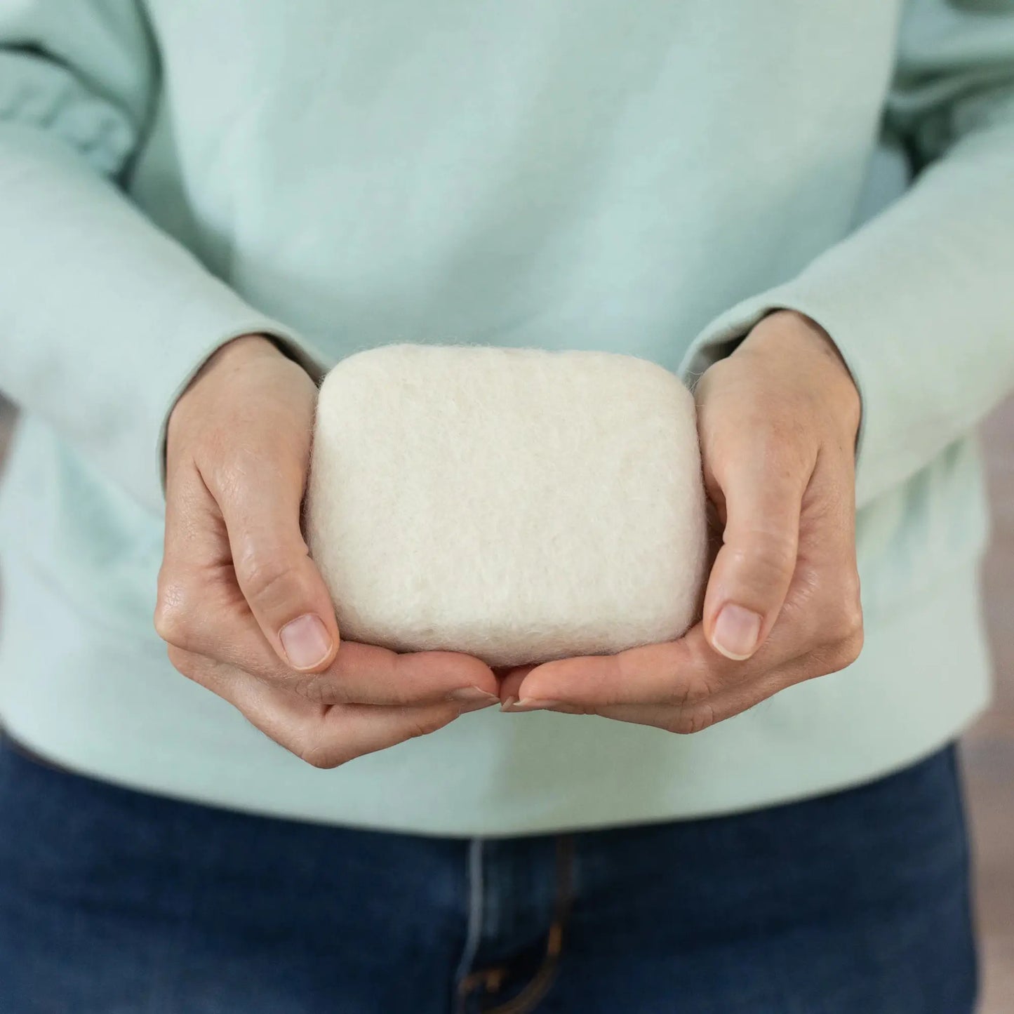 Person holding a small needle felting mat in their hands