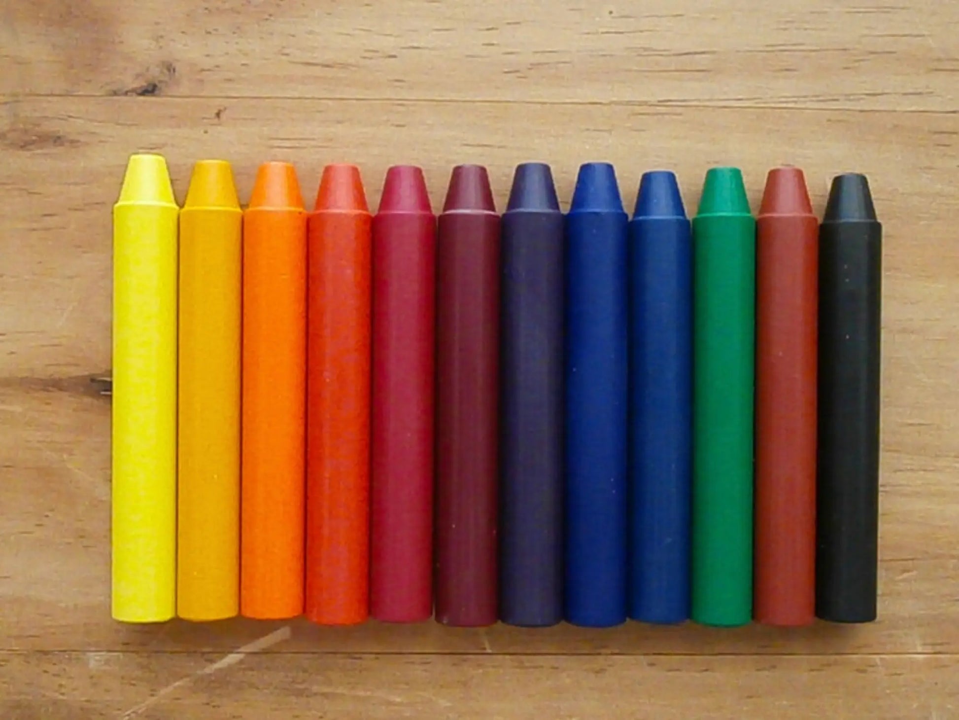 Row of colorful crayons on a wooden surface