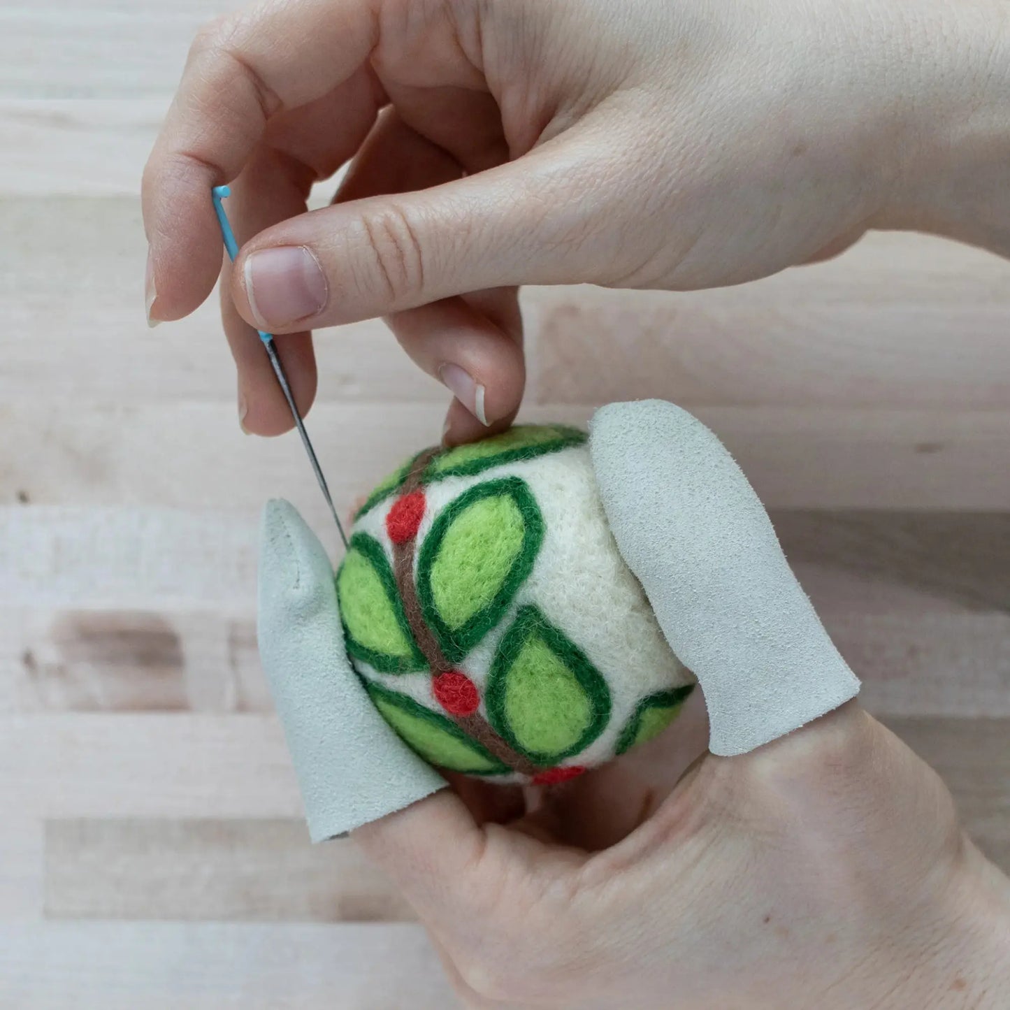 Hands wearing Needle Felting Finger Guards while Needle Felting a felt ornament