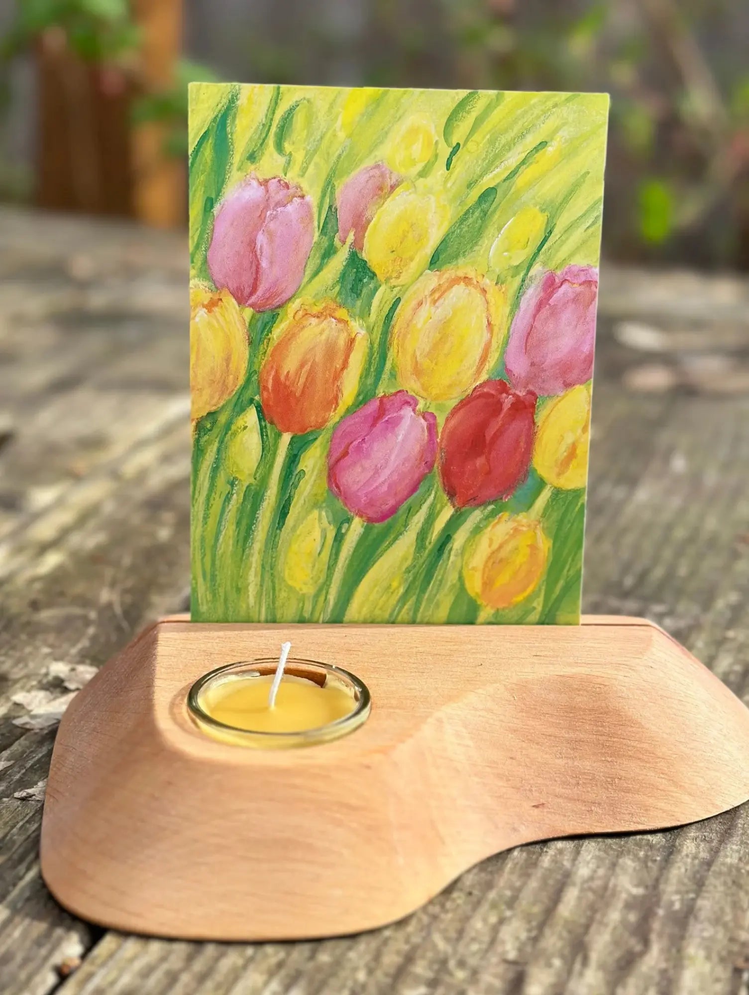 Wooden candle holder with a card featuring tulip illustration on a wooden surface.