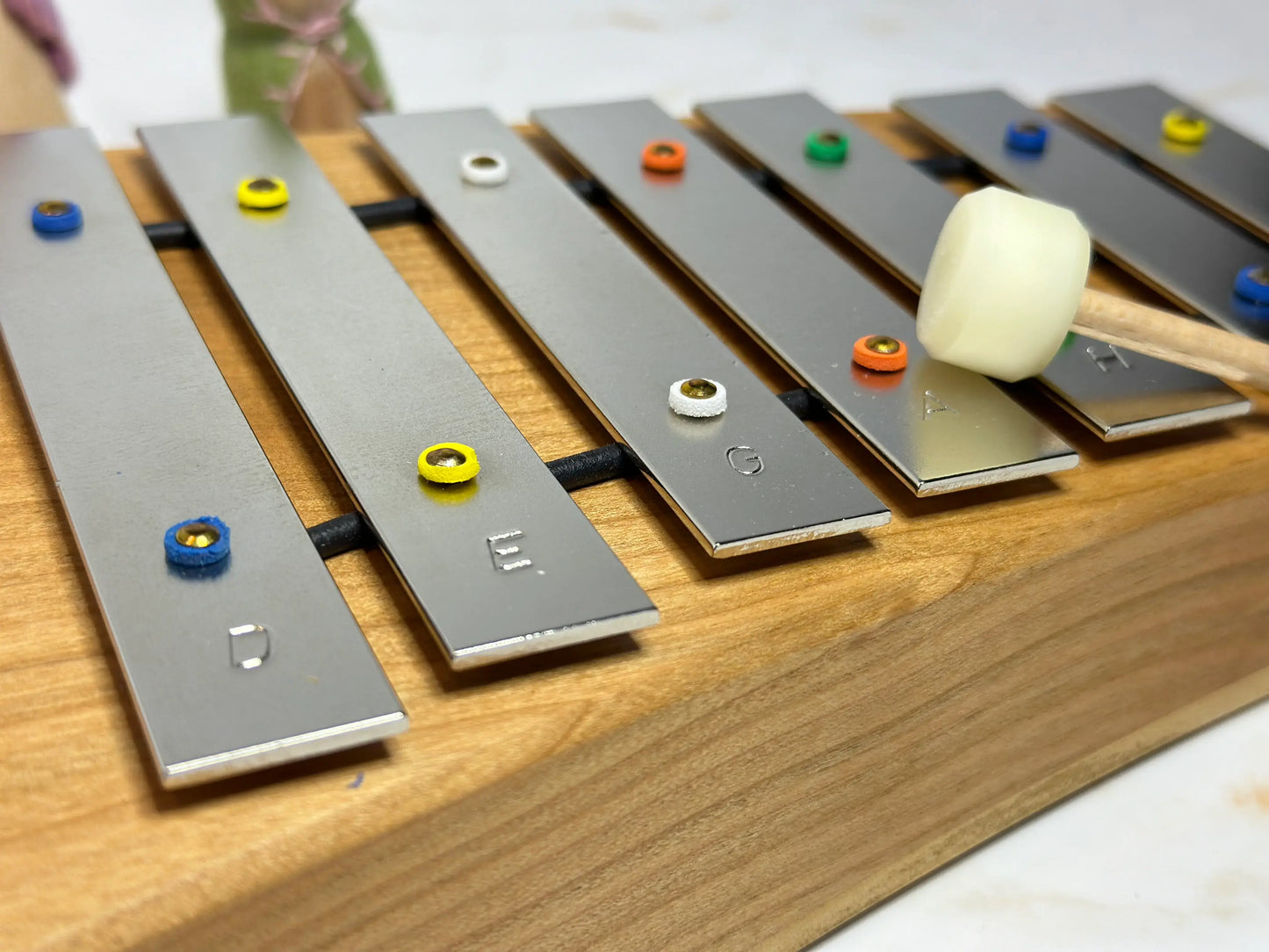Metallic xylophone with colorful mallets on a wooden surface
